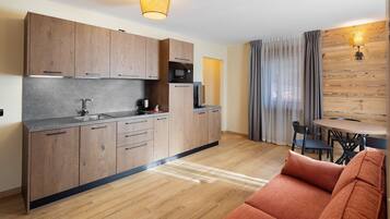 A modern kitchen with wooden cabinets, a microwave, and a sink. There is a dining area with a table and chairs.