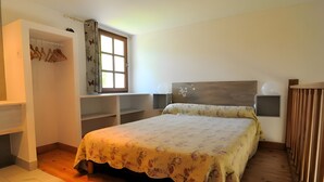 A bedroom with a bed, a wardrobe, a window, and a bedside table.