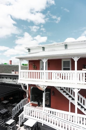 A two-story building with a balcony, a staircase, and a brick facade.