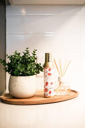 A potted plant, a bottle with a spray nozzle, and reed diffuser sticks on a wooden tray.