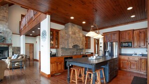 Una cocina amplia con una isla grande, armarios de madera y una chimenea de piedra.
