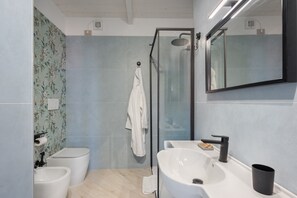 A modern bathroom with a glass-enclosed shower, a white sink, and a bidet. - Apartment 'Deluxe Zenone' with Sea View, Wi-Fi and Air Conditioning (Ascea)