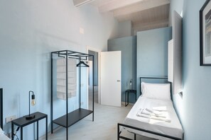 A bedroom with a bed, a hanging clothes rack, a bedside table with a lamp, and a door leading to another room. - Apartment 'Deluxe Zenone' with Sea View, Wi-Fi and Air Conditioning (Ascea)