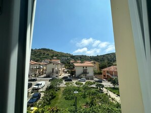 A residential area with houses, a street, and a hilly landscape in the background.