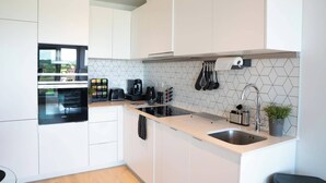 Una cocina moderna con armarios blancos, encimera negra y salpicadero de azulejos hexagonales.