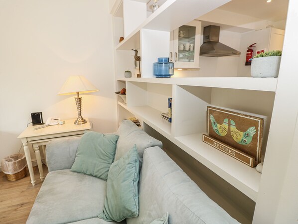 A living room with a sofa, a lamp, a small table, and shelves with various items. - Vermont 4 (Yarmouth)