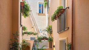 A narrow corridor with a staircase, walls adorned with potted plants, and a visible door at the end. - Apartment 'Deluxe Melisso' with Wi-Fi and Air Conditioning (Ascea)