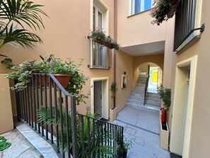 Un passadís interior estret amb una escala, plantes en testos i un extintor.
