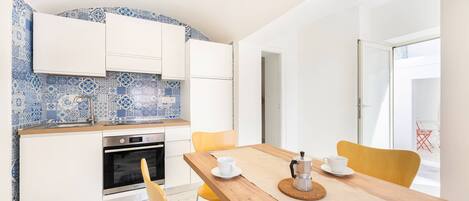 Een koelkast, een kookplaat, kookgerei, borden en bestek, een eettafel