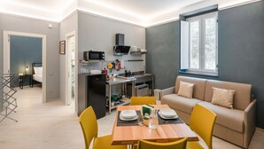 Un espace de vie compact comprenant un coin cuisine, un coin repas et un coin salon.