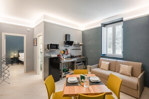 Un ambiente compatto con angolo cottura, zona pranzo e salotto.