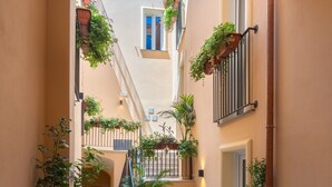 Un couloir étroit avec un escalier, des plantes en pot et une porte au fond.