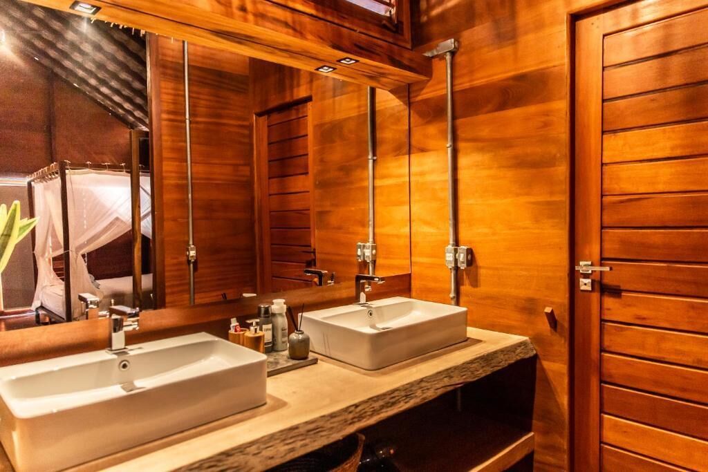 Un baño de madera con dos lavamanos, un espejo grande y zona de ducha.