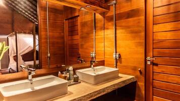 Un baño de madera con dos lavamanos, un espejo grande y zona de ducha.