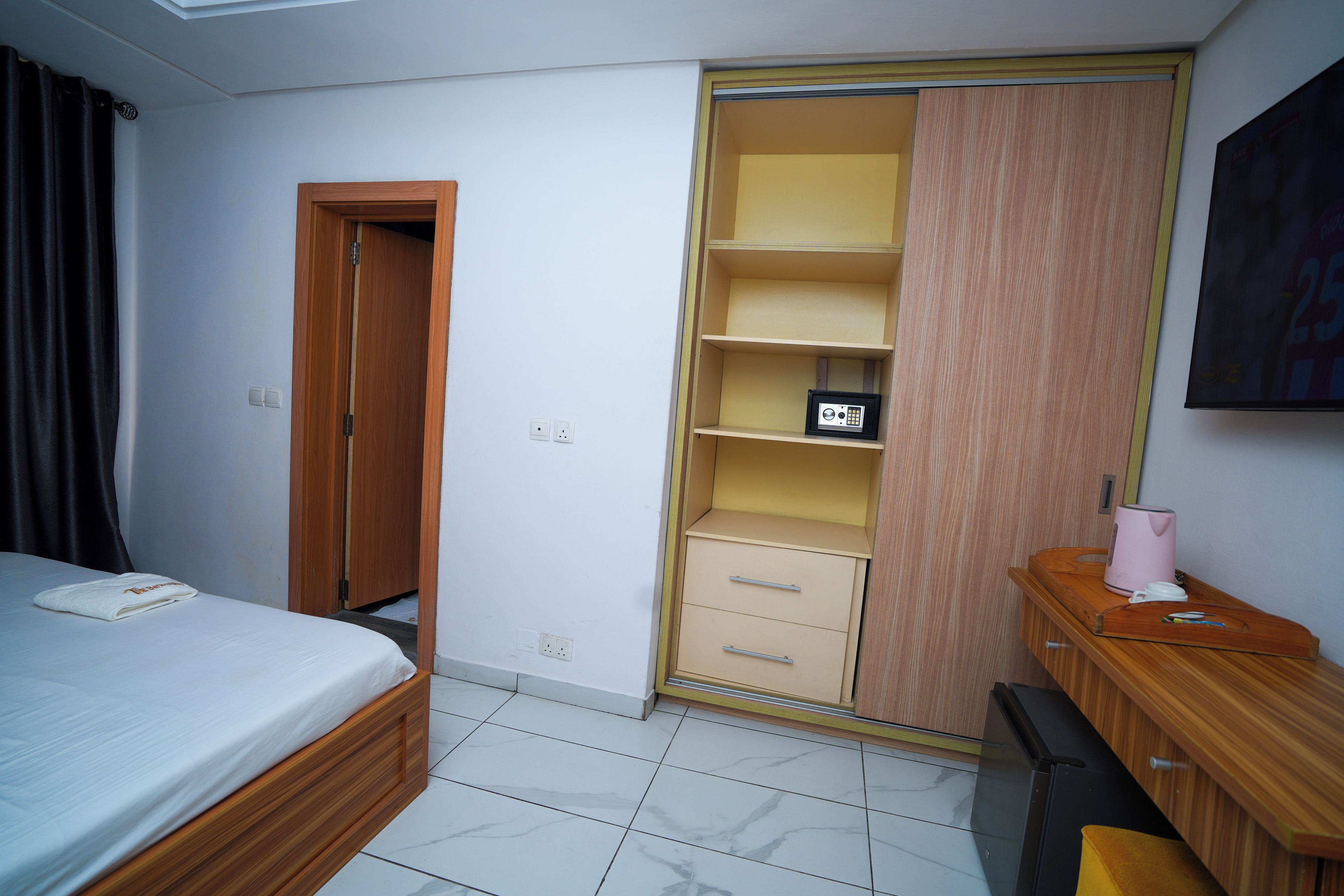 A hotel room with a bed, a wardrobe, a desk, and a television.