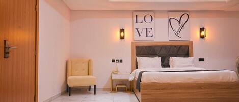 A bedroom with a bed, a chair, a nightstand, and wall art.