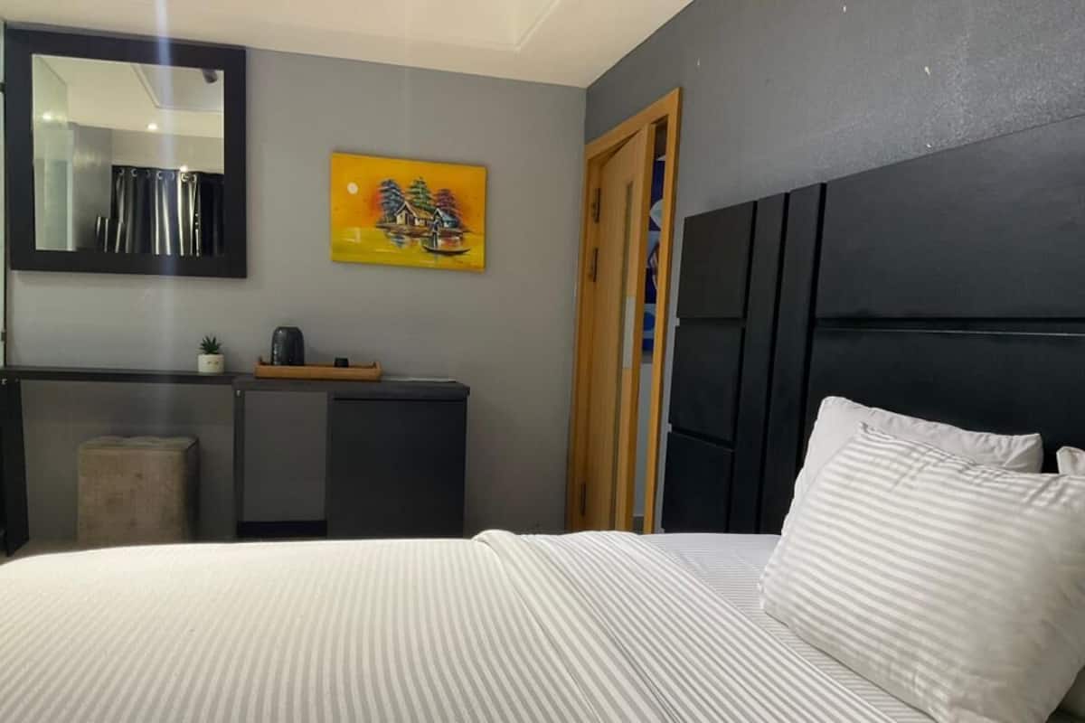 Un dormitorio con cama, cómoda, espejo y un cuadro en la pared.