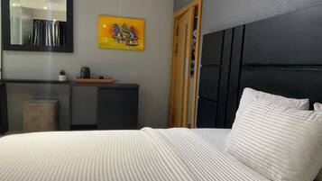 Ett sovrum med en säng, en byrå, en spegel och en tavla på väggen.