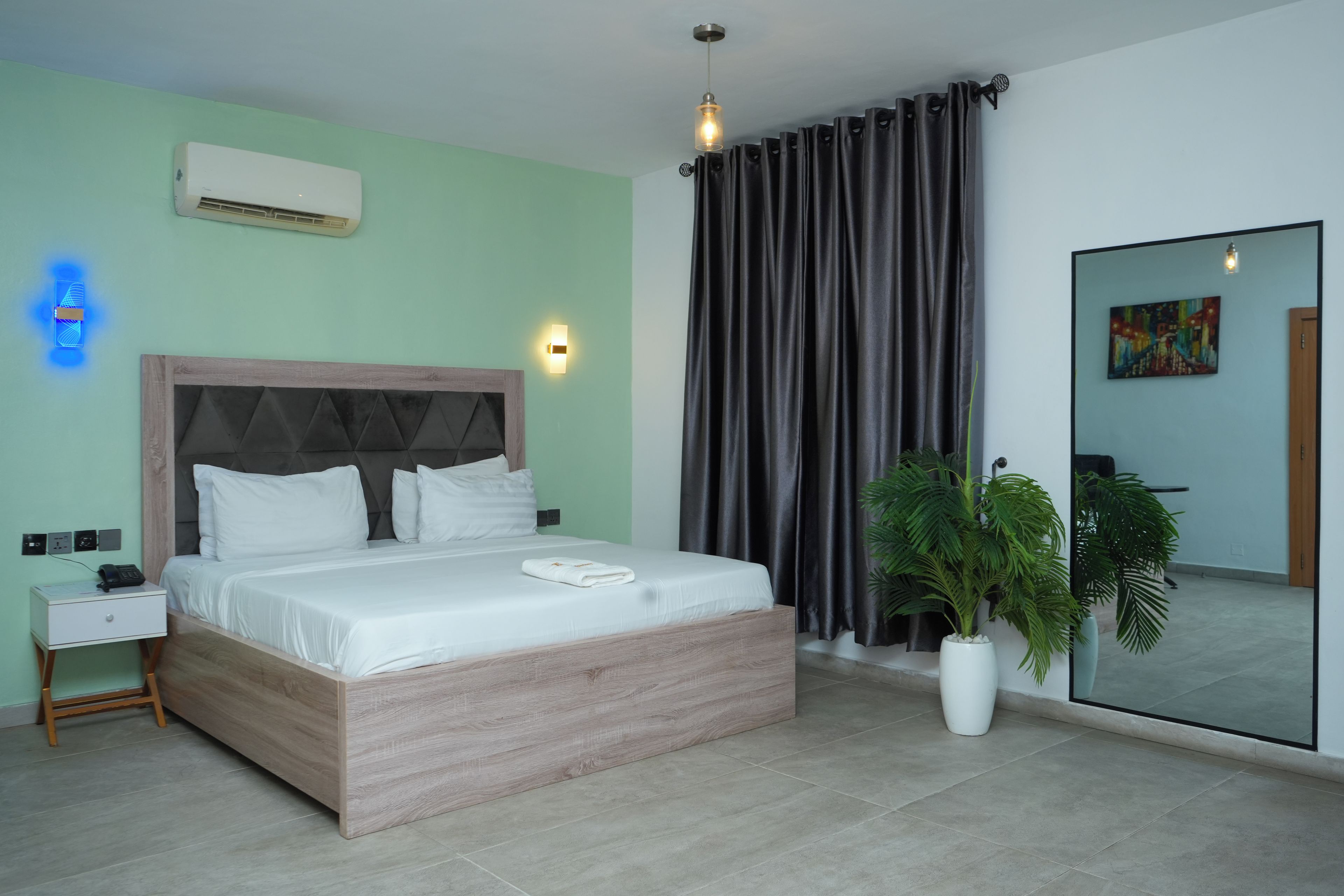 A modern hotel room with a bed, bedside table, and a large mirror.