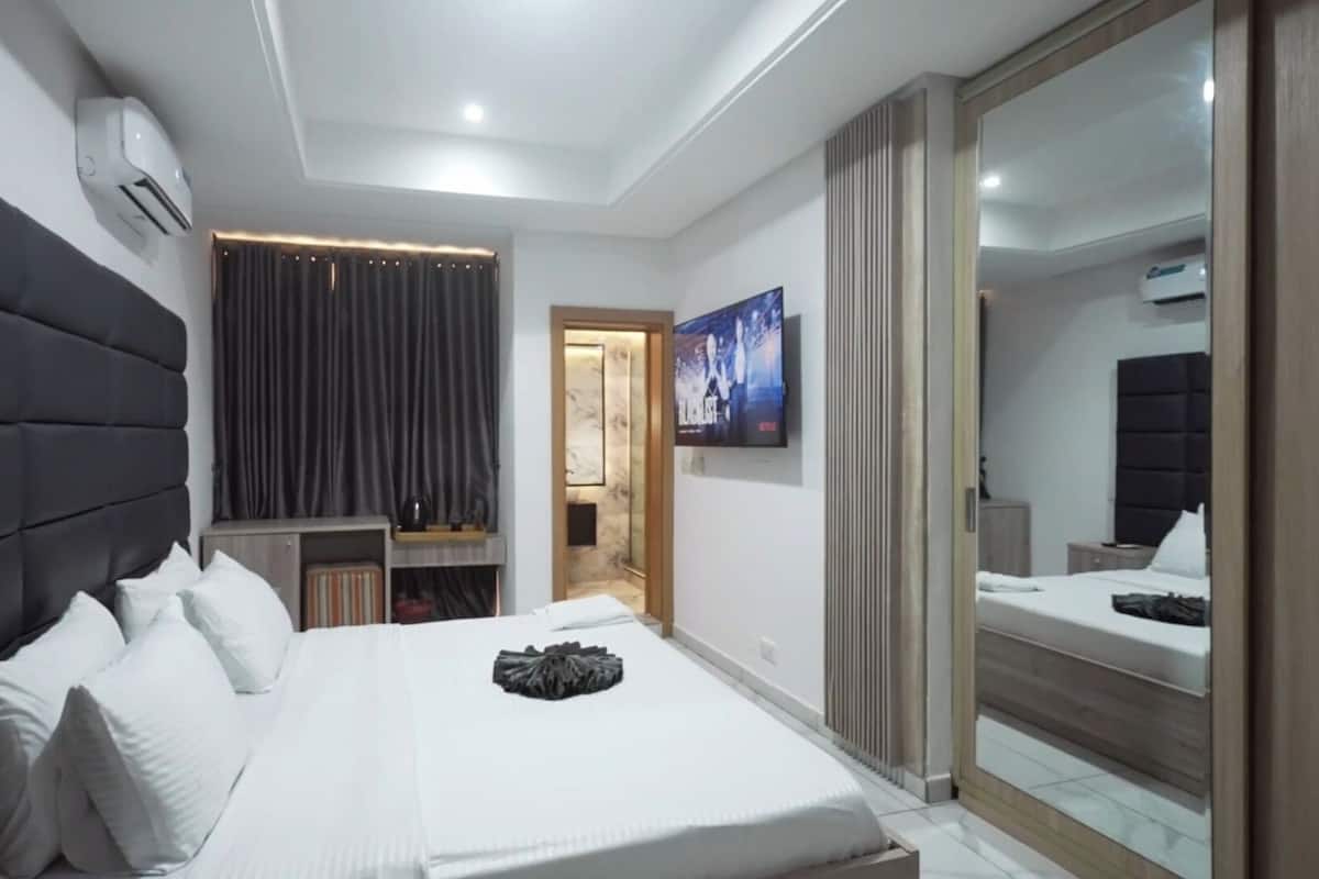 Un dormitorio moderno con una cama grande, un televisor y un vestidor.