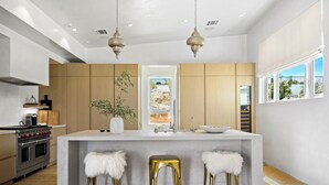 Une cuisine moderne dotée d’un îlot central, d’appareils électroménagers en acier inoxydable et d’armoires en bois.