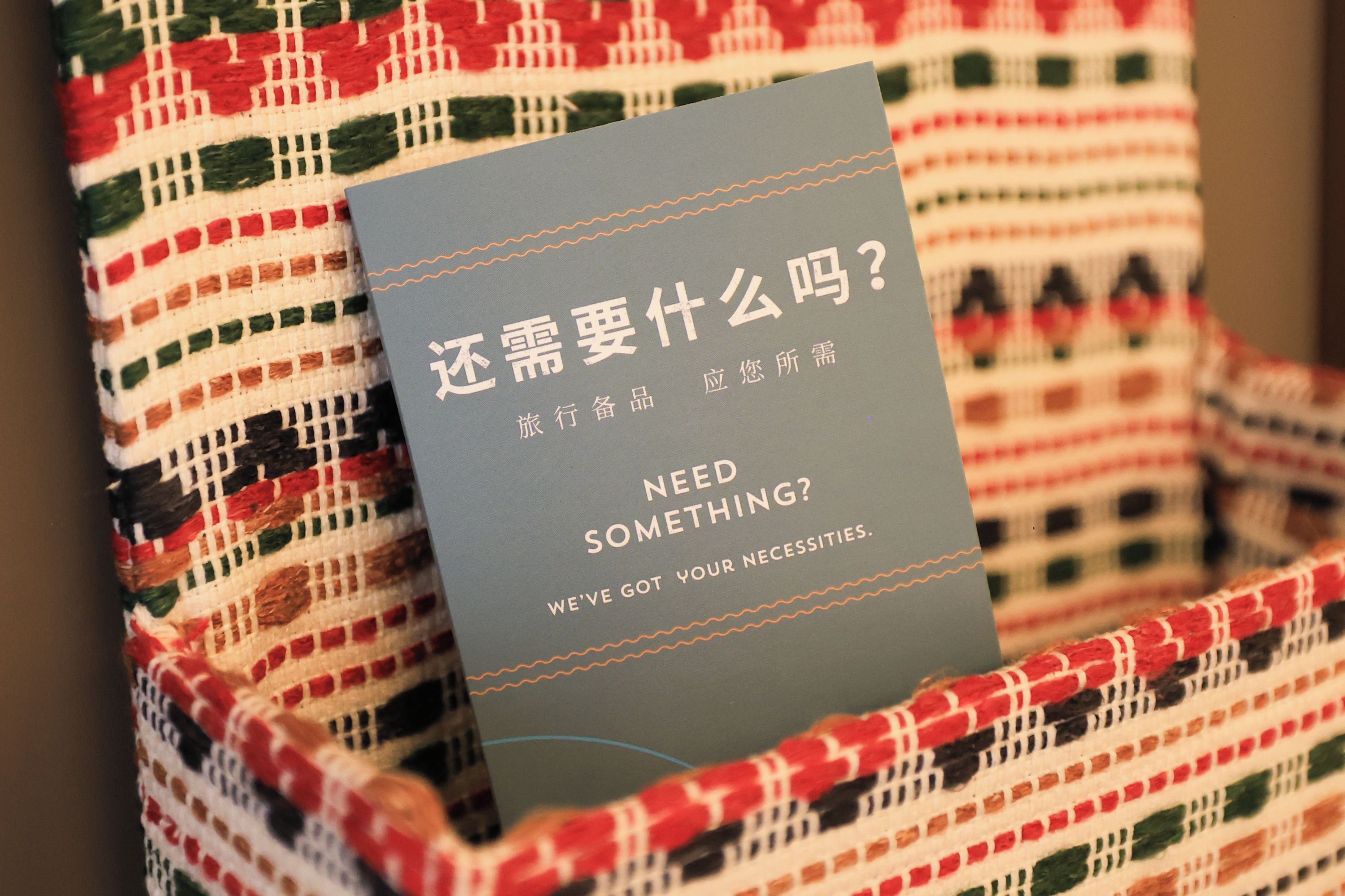 A card with text in a foreign language and English, placed on a woven fabric.