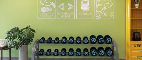 A fitness wall with motivational posters, a dumbbell rack, and a yellow cabinet.