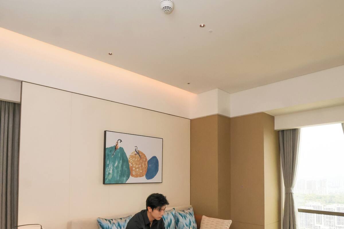 A modern hotel room with a sofa, a coffee table, a lamp, and a painting on the wall.