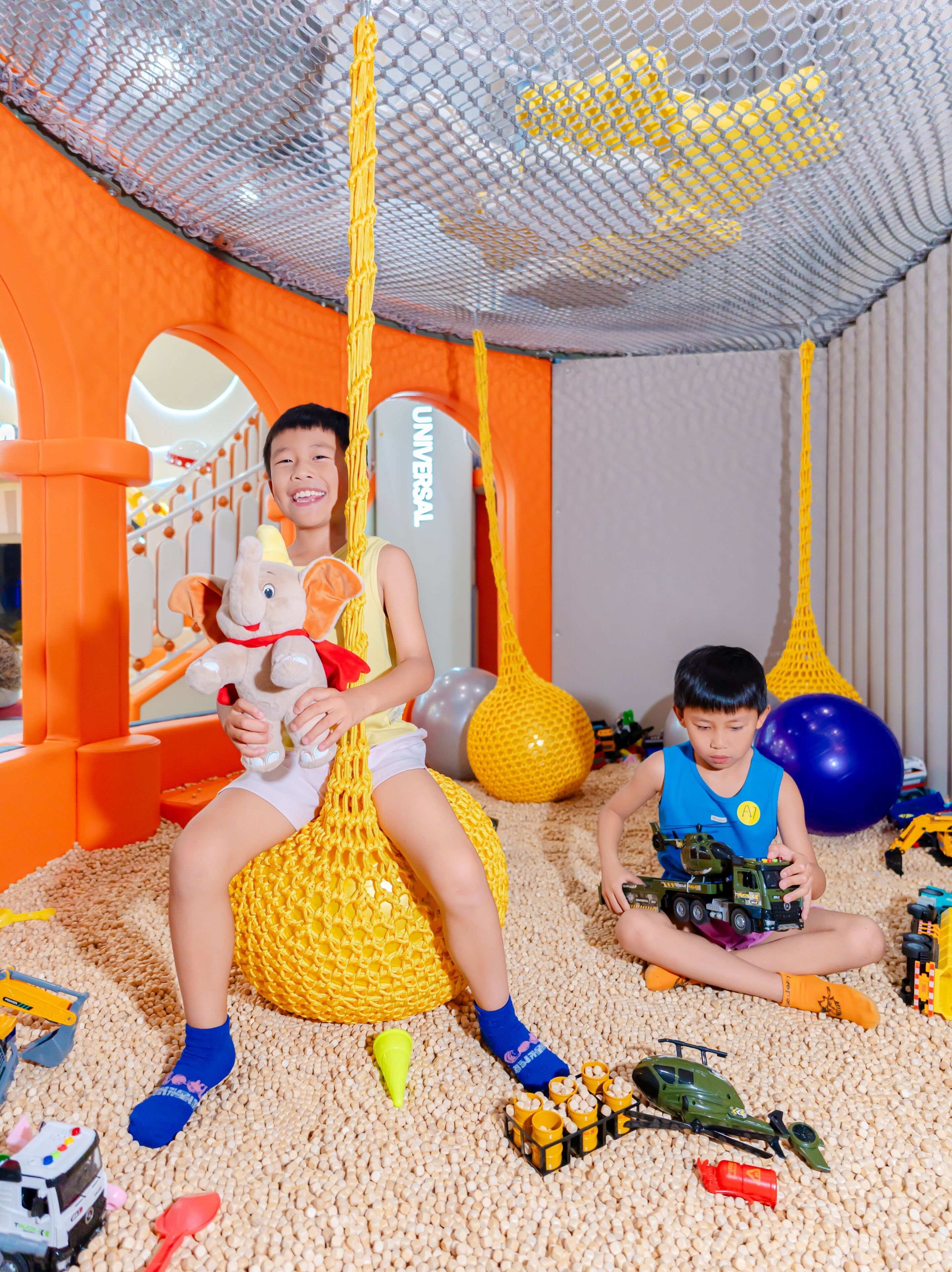 A play area with a netted ceiling, a ball pit, and various toys.