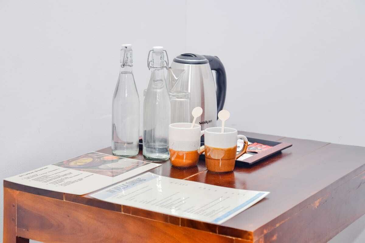 A wooden reception desk with a coffee maker, two thermoses, and two mugs with coffee.