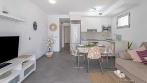 Una sala moderna con televisor de pantalla plana, una mesa de comedor, sillas y un sofá.