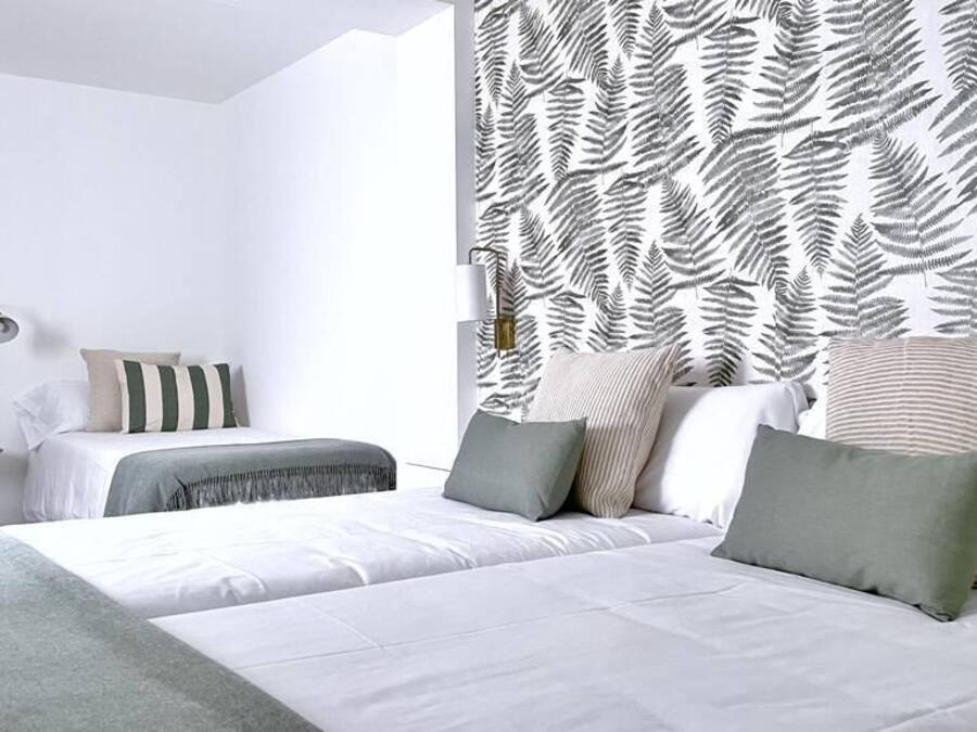 Un dormitorio moderno con una cama grande, dos mesitas de noche y una cortina estampada.