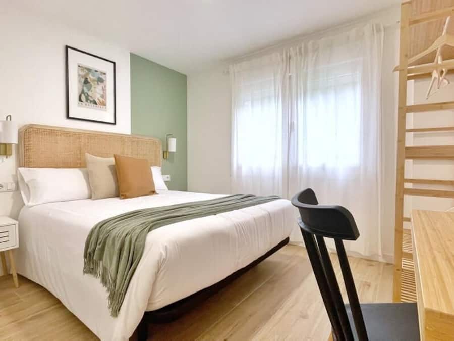 A bedroom with a bed, bedside table, and a wooden chair.