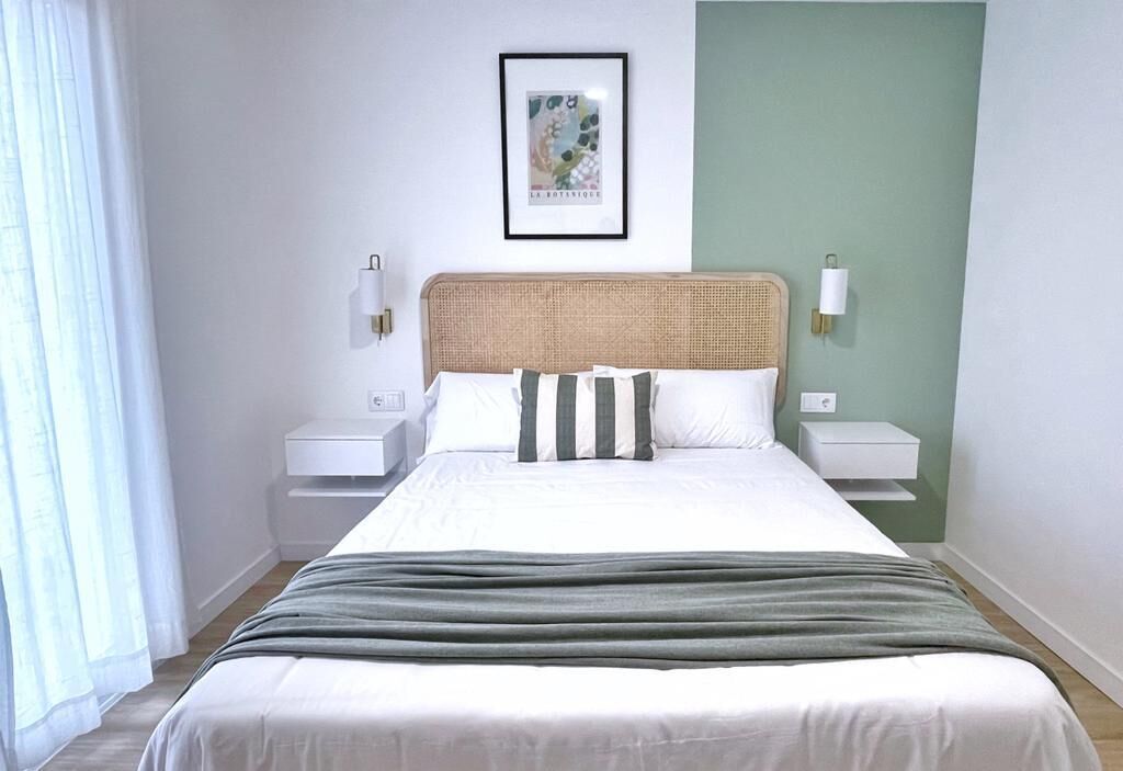 A neatly arranged bedroom with a bed, bedside tables, and a framed picture on the wall.
