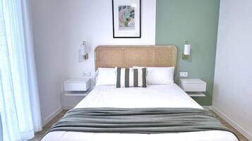 A neatly arranged bedroom with a bed, bedside tables, and a framed picture on the wall.
