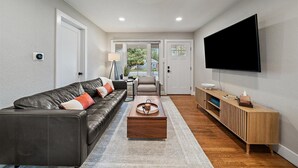 A modern living room with a leather sofa, a wooden coffee table, and a TV mounted on the wall.