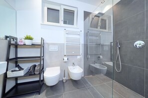 A modern bathroom with a toilet, bidet, and glass-enclosed shower.