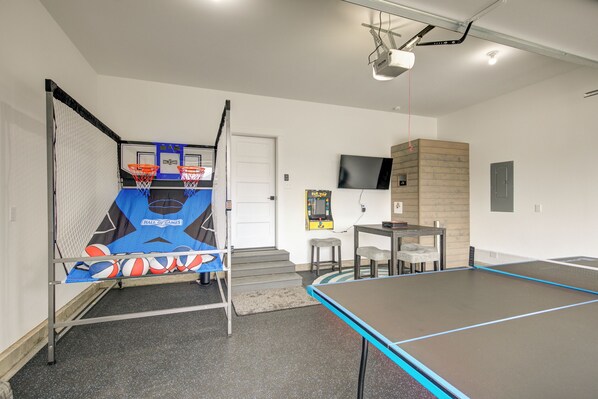 Une salle de loisirs équipée d’une table de ping-pong, d’un panier de basket et d’un petit coin salon.