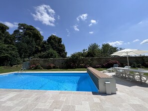 A swimming pool with a wooden deck and lounge chairs. - Chateau in Sarthe With Heated Pool (Dangeul)