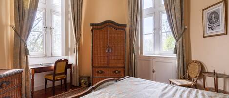 Un dormitorio con una cama grande, un armario de madera, un escritorio con una silla y una ventana con cortinas.