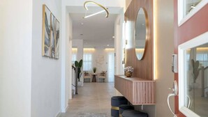 Un pasillo moderno con una consola de madera, un espejo grande y una escalera que conduce a otra habitación.