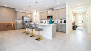 Una cocina moderna con una isla central, taburetes de bar y electrodomésticos de acero inoxidable.