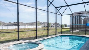 Una piscina con hidromasaje, rodeada por una estructura de vidrio, con vistas a casas al fondo.