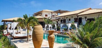 A resort with multiple villas, a swimming pool, and palm trees.