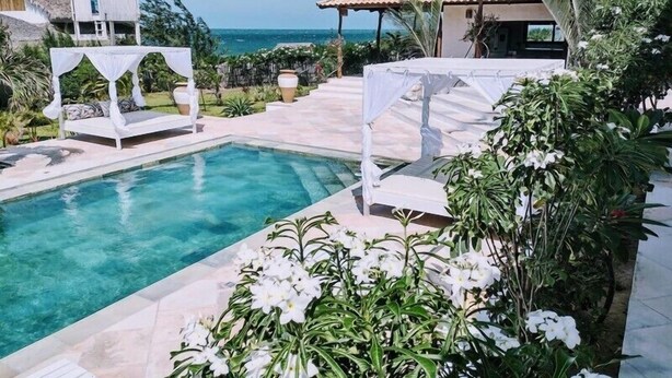 A pool area with a clear view of the ocean, a white gazebo, and a building with a tiled roof. - Villa Pinolo (Cruz)