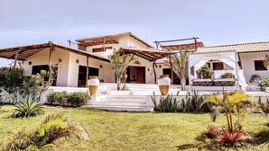 A two-story house with a covered patio and a small garden area. - Villa Pinolo (Cruz)