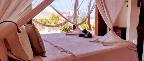 Una cama con dosel, almohadas y una colcha.