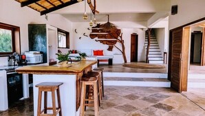 A spacious kitchen with a large island, wooden stools, and a rustic ceiling. - Villa Pinolo (Cruz)