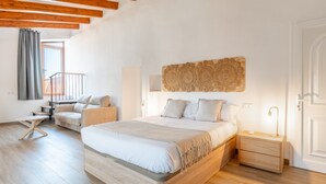 Een slaapkamer met een houten bed, een nachtkastje, een slaapbank en een groot raam.