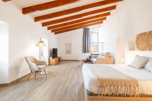 Un dormitorio con una cama grande, un escritorio, una silla, un televisor y una ventana con cortinas.